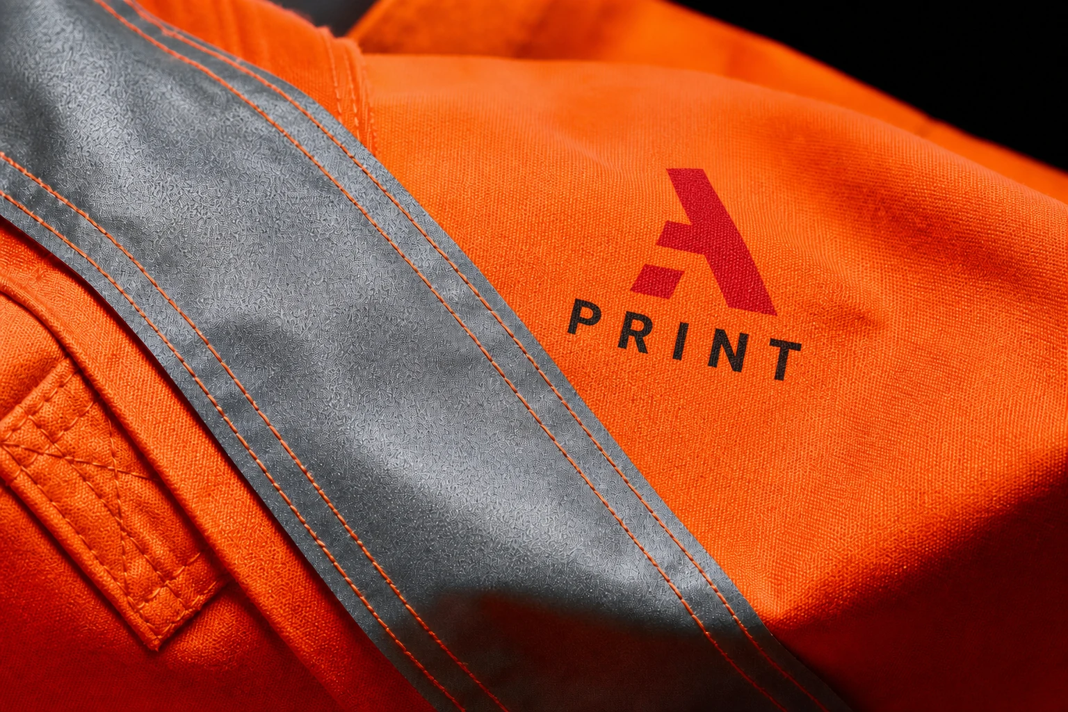 Close-up of a 3A Print logo printed beside reflective tape on orange high-vis workwear